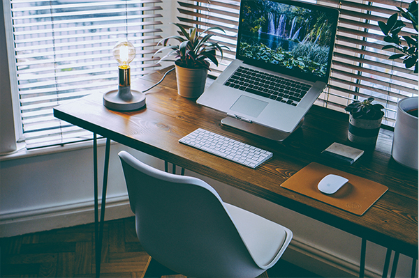 Home office setup with laptop, secondary keyboard and mouse, on desk behind a chair